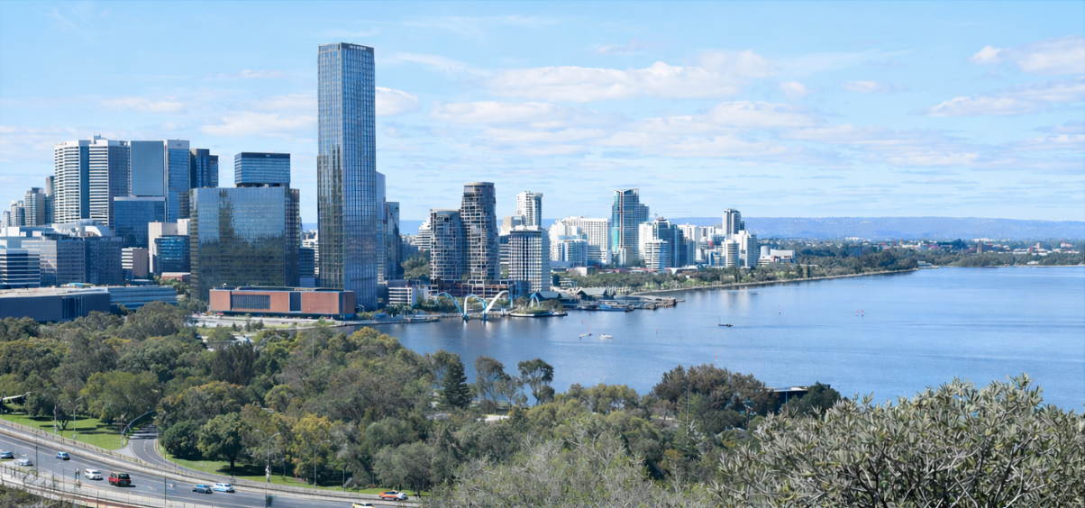 A wide panoramic view of a modern city skyline situated along a calm river
